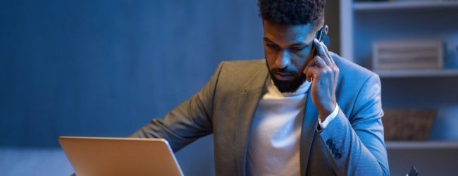 young-african-american-businessman-making-phone-call-indoors-in-office-at-night.jpg