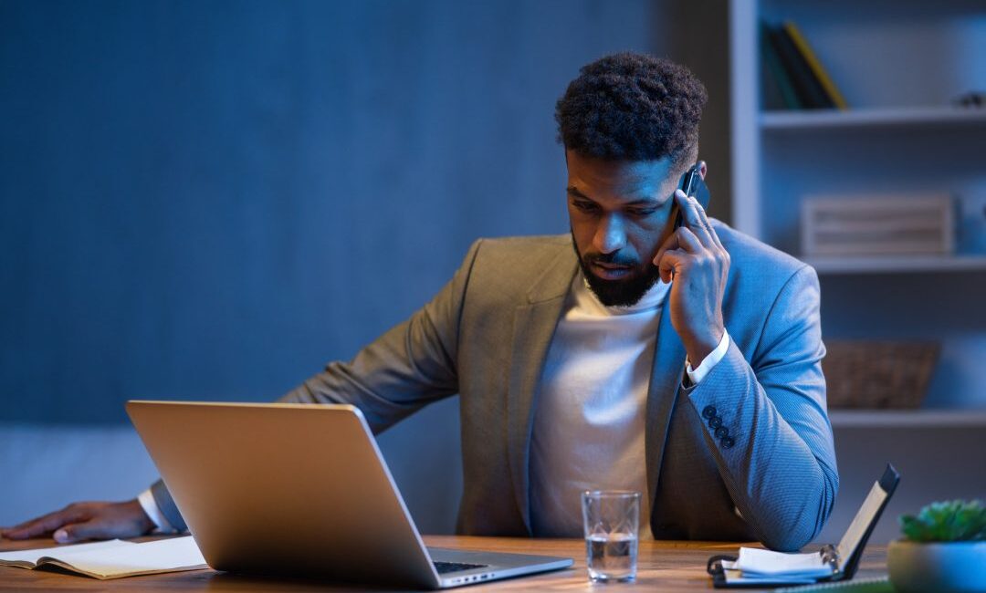 young-african-american-businessman-making-phone-call-indoors-in-office-at-night.jpg